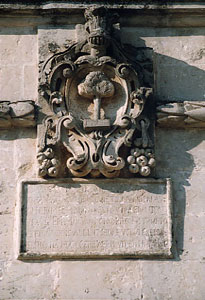 Arme del Comune di Melpignano e targa epigrafica posta nel 1694, a ricordo della ricostruzione degli antichi portici in piazza san Giorgio.